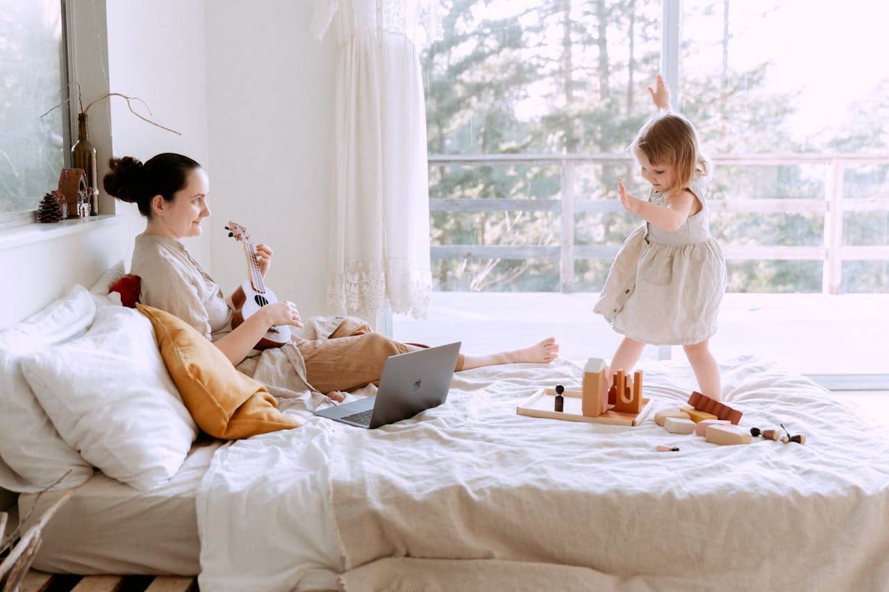 Happy young woman playing ukulele for daughter at home